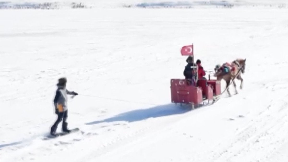 Çıldır Gölü’nün buz tutan yüzeyinde atlı snowboard yapan bir ziyaretçi,